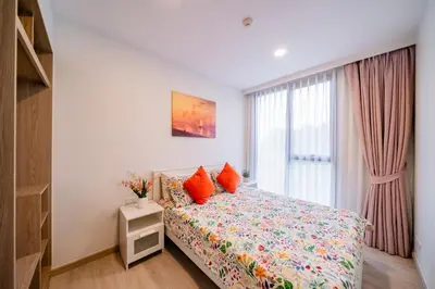 a bedroom with a bed with orange pillows and a window at Sky park 2 bedroom 60m2 in Laguna Phuket