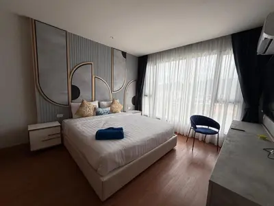 a bedroom with a large white bed and a chair at Bellevue Bangtao 2 bedrooms in Laguna Phuket