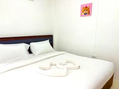 a bedroom with a white bed with a wooden headboard at Patong Canal Villa 109 in Patong Beach