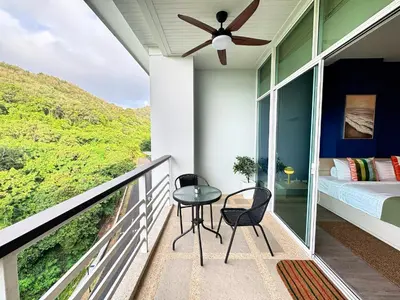 a balcony with a bed and a table and chairs at Veloche Peaceful Condo In Karon Beach in Karon Beach