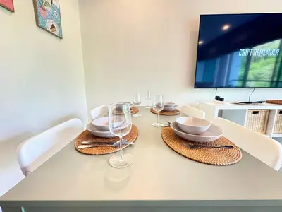 a dining room table with wine glasses and a television at Veloche Peaceful Condo In Karon Beach in Karon Beach