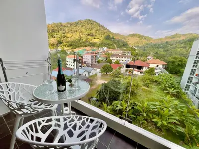 a table with two chairs and a bottle of wine on a balcony at Chic Condominium A 518 in Karon Beach