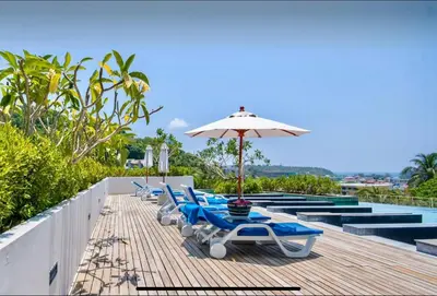 a row of lounge chairs and an umbrella on a deck at Veloche 2 Floor in Karon Beach
