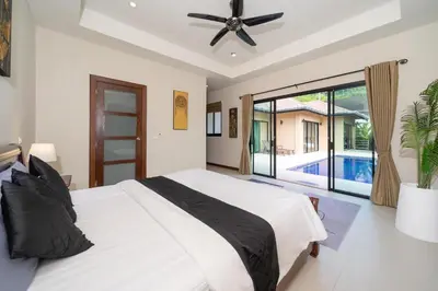 a bedroom with a white bed with a ceiling fan at Naiharn Beach 4 Bedroom Villa in Nai Harn Beach