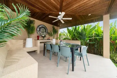an outdoor dining area with a black table and blue chairs at Naiharn Beach 4 Bedroom Villa in Nai Harn Beach