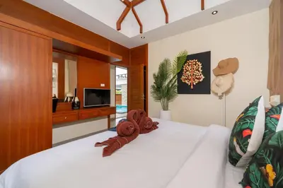 a bedroom with a bed with white sheets and a television at Rawayana Beach Villa 3D14 in Phuket Town