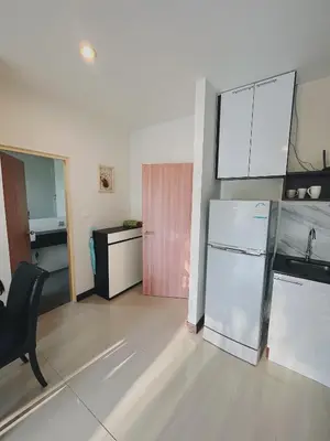 a kitchen with a refrigerator and a table and a chair at Chic 10 minutes to reach the karon beach, with free swimming pool and gym, WIFI in Karon Beach