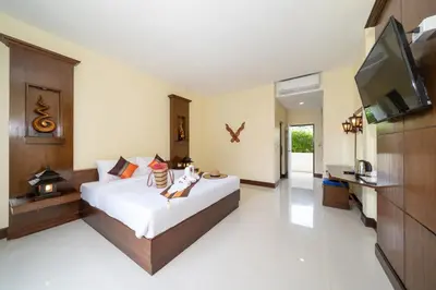 a bedroom with a bed and a flat screen tv at JR Siam Inn Resort in Kata Beach