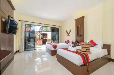 a hotel room with two beds and a television at JR Siam Inn Resort in Kata Beach