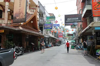 a man walking down a street in a city at Tulip Inn in Patong Beach