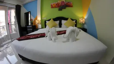 a bedroom with a large white bed with towels on it at Tulip Inn in Patong Beach