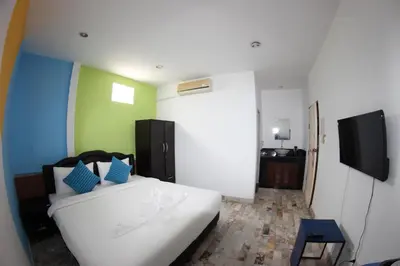 a bedroom with a white bed and a flat screen tv at Tulip Inn in Patong Beach
