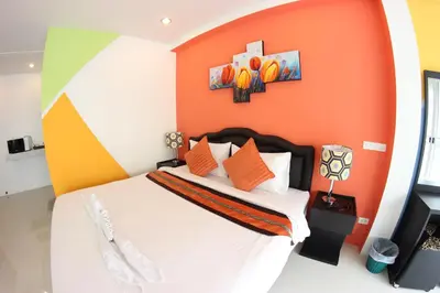 a bedroom with a bed with an orange wall at Tulip Inn in Patong Beach