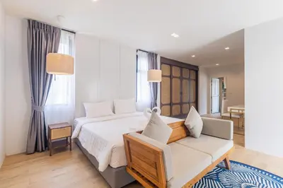 a bedroom with a white bed and a couch at Bee Villa Wellness Resort Phuket in Laguna Phuket