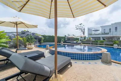 a pool with chairs and an umbrella next to a pool at Bee Villa Wellness Resort Phuket in Laguna Phuket