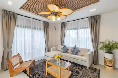 a living room with a couch and a ceiling fan at Bee Villa Wellness Resort Phuket in Laguna Phuket