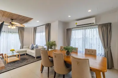 a dining room and living room with a table and chairs at Bee Villa Wellness Resort Phuket in Laguna Phuket