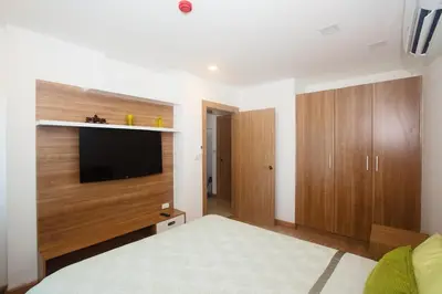 a bedroom with a bed and a flat screen tv at Calypso Condo Naiharn in Phuket Town
