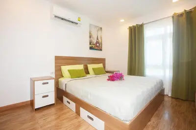 a bedroom with a bed with yellow and green pillows at Calypso Condo Naiharn in Phuket Town
