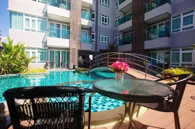 a patio with a table and chairs next to a swimming pool at Calypso Condo Naiharn in Phuket Town