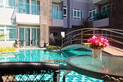 a swimming pool with a table and flowers on it at Calypso Condo Naiharn in Phuket Town