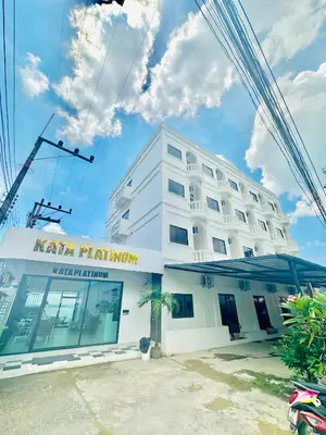 a white building with a palm tree in front of it at Kata Platinum in Kata Beach