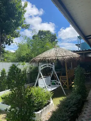 a straw umbrella and a chair in a yard at 3P Phuket Airport Hotel in Phuket