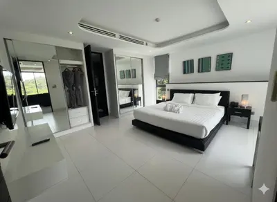 a bedroom with a white bed and a fireplace at Twin Sand Phuket by PPR in Patong Beach