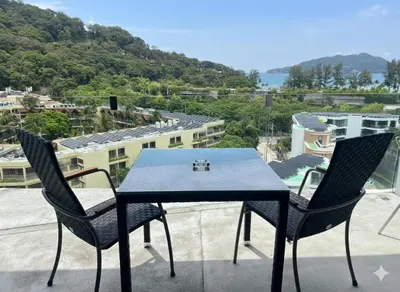 a blue table and two chairs on a balcony at Twin Sand Phuket by PPR in Patong Beach