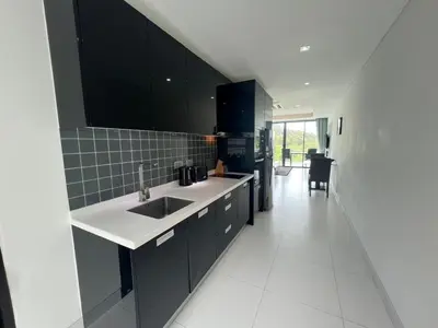 a kitchen with black cabinets and a white sink at Twin Sand Phuket by PPR in Patong Beach