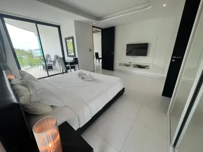 a bedroom with a large white bed and a television at Twin Sand Phuket by PPR in Patong Beach