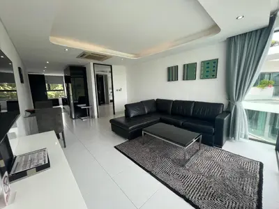 a living room with a black couch and a table at Twin Sand Phuket by PPR in Patong Beach