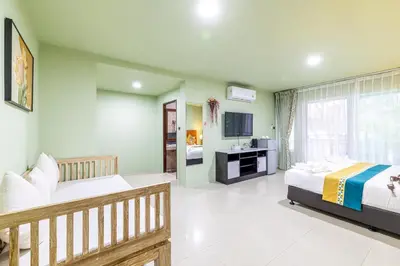 a large room with two beds and a television at Phuket Leisure Time Hotel in Rawai Beach