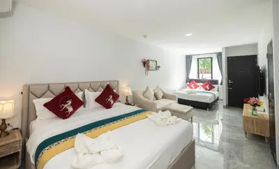 a bedroom with a large bed and a living room at Phuket Leisure Time Hotel in Rawai Beach