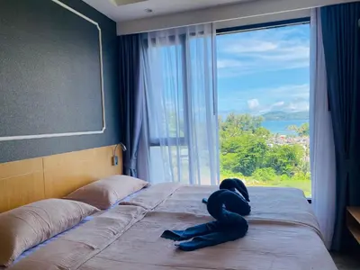 a stuffed animal on a bed in a room with a window at Aristo 2 Condo with a sea view in Surin Beach