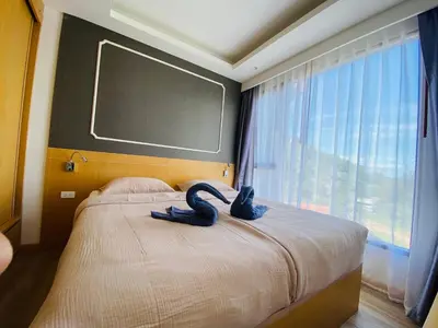 a bedroom with a large bed with a large window at Aristo 2 Condo with a sea view in Surin Beach