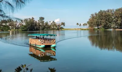 a boat on a river with its reflection in the water at Laguna Park 5 bedroom villa with pool in Laguna Phuket near the beach in Laguna Phuket