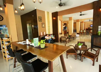 a restaurant with a large wooden table and chairs at Breezotel - SHA Certified in Patong Beach