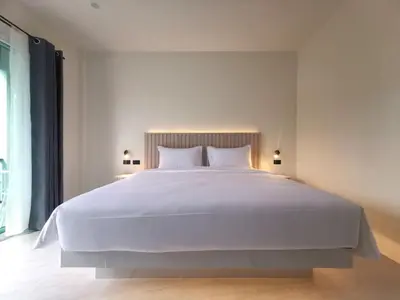 a bedroom with a large white bed with two lamps at The Pinda House Bangtao in Bang Tao Beach