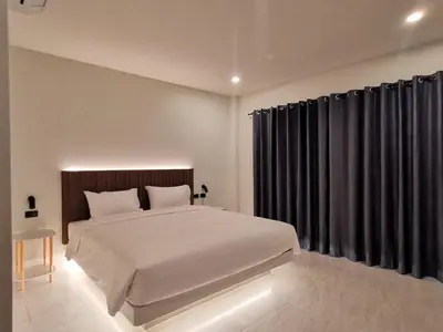 a bedroom with a large bed and black curtains at The Pinda House Bangtao in Bang Tao Beach