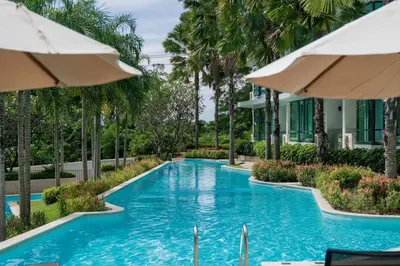 a swimming pool with trees and umbrellas at La Vita 5 star Super 1 Bdr Nai Harn Beach in Rawai Beach
