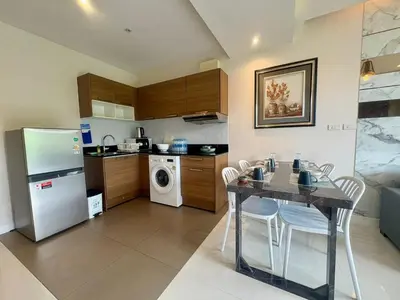 a kitchen with a table with chairs and a refrigerator at The Lago Nai Harn 2 BR-Walk to beach by ALL HOMES in Rawai Beach