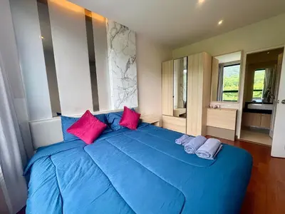 a blue bed with pink pillows in a bedroom at The Lago Nai Harn 2 BR-Walk to beach by ALL HOMES in Rawai Beach