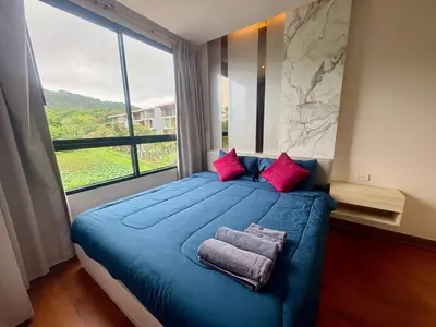 a bedroom with a blue bed with a large window at The Lago Nai Harn 2 BR-Walk to beach by ALL HOMES in Rawai Beach