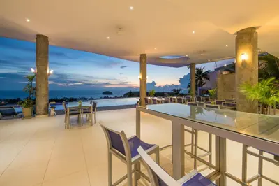an outdoor patio with a bar and chairs at The View Phuket By RESAVA in Kata Beach