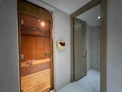 a bathroom with a wooden door and a sink at The View Phuket By RESAVA in Kata Beach