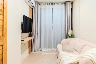 a living room with a white couch and a window at Zcape 1 By SilqStay in Ban Thalat Choeng Thale