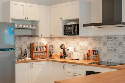 a kitchen with white cabinets and a wooden counter top at Nai Harn Beach Holiday Home - Rawai in Rawai Beach