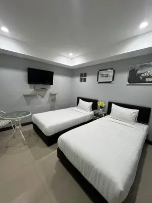 a room with two beds and a table and a tv at PMS Guest House Patong in Patong Beach