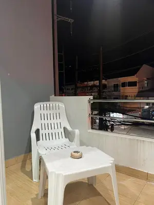 a white chair and a table in front of a window at PMS Guest House Patong in Patong Beach